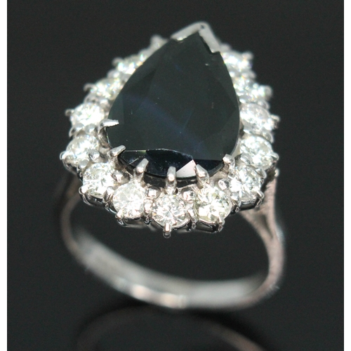 155 - A sapphire and diamond cluster ring, the dark blue pear cut stone weighing approx. 6.21 carats, surr... 