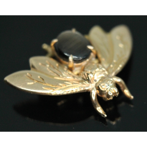 70 - A novelty brooch modelled as a bee and set with a synthetic six ray star sapphire, marked '14K' and ... 