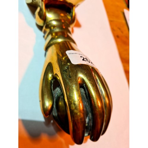 262 - A 19th century brass door knocker in the form of a hand holding a ball