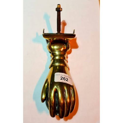 262 - A 19th century brass door knocker in the form of a hand holding a ball