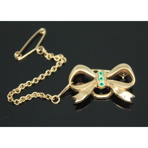 122 - A 9ct gold emerald brooch of bow form, sponsor's mark 'CG&S', length 22mm, gross wt. 3.63g.