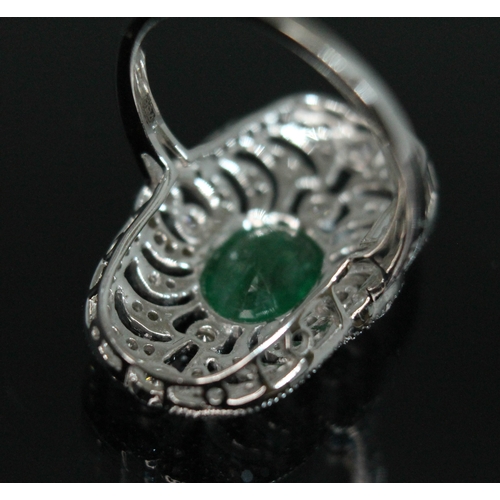 149 - An 18ct white gold emerald and diamond ring, the central oval cut emerald approx. 1.08ct, surround b... 