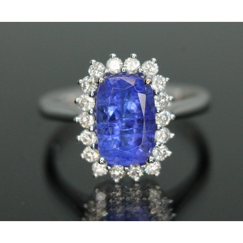 153 - A tanzanite and diamond cluster ring, the four claw set cushion cut tanzanite weighing approx. 3 car... 