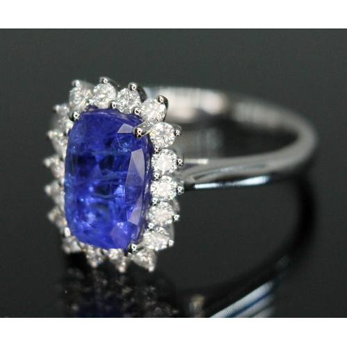 153 - A tanzanite and diamond cluster ring, the four claw set cushion cut tanzanite weighing approx. 3 car... 