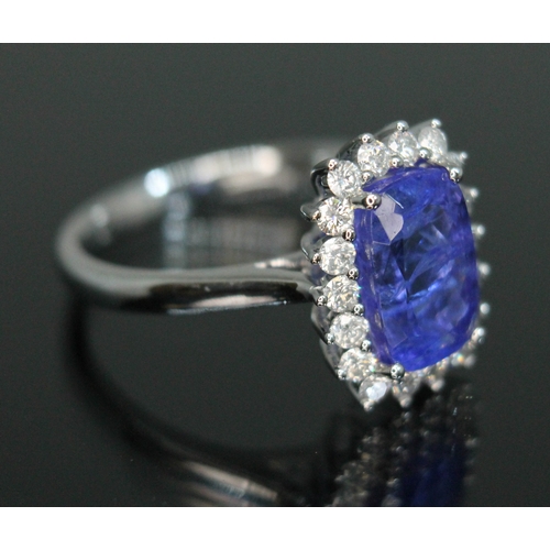 153 - A tanzanite and diamond cluster ring, the four claw set cushion cut tanzanite weighing approx. 3 car... 