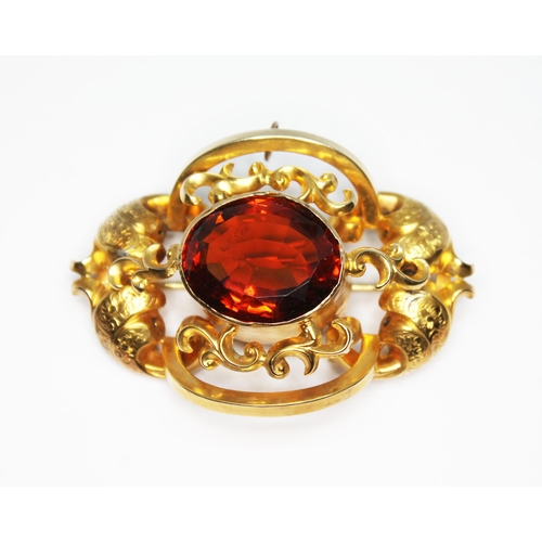 101 - A 19th century yellow metal brooch of scroll form and set with an oval mixed cut orange citrine weig... 