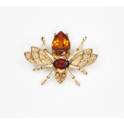 109 - A novelty brooch modelled as a bee and set with a citrine and a garnet, marked '10K', length 3.42g.