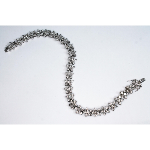 125 - An 18ct white gold diamond bracelet, formed from twenty five stone flower heads, total approx. diamo... 