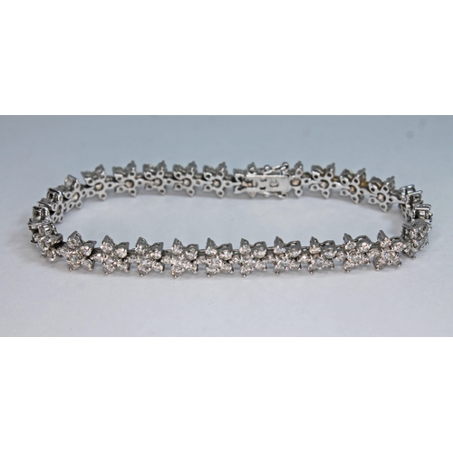 125 - An 18ct white gold diamond bracelet, formed from twenty five stone flower heads, total approx. diamo... 