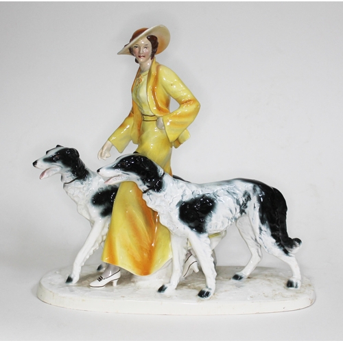 216 - An Art Deco Goldscheider style figure of a woman walking two borzoi dogs, height 35cm and width 37cm... 