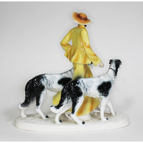 216 - An Art Deco Goldscheider style figure of a woman walking two borzoi dogs, height 35cm and width 37cm... 