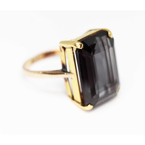 106 - A synthetic colour change sapphire ring, the central emerald cut stone weighing approx. 13.13ct, ban... 