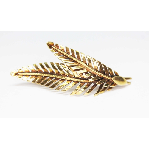 151 - A modern brooch formed from two fern leaves, marked '585', length 44mm, wt. 3.8g.