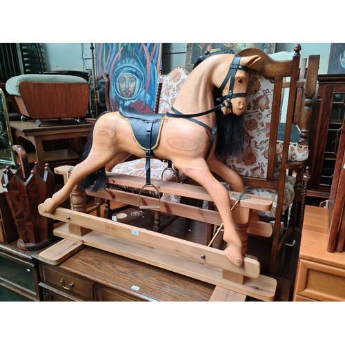 878 - A pine rocking horse with leather saddle and stirrups.