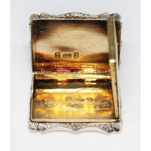 227 - An early Victorian silver vinaigrette, of scroll form and engraved all over, hinged lid revealing gi... 