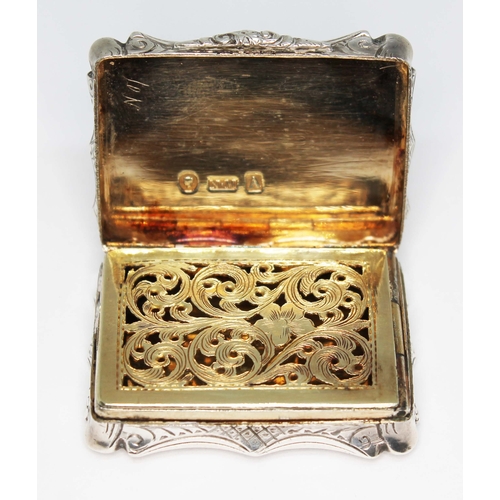 227 - An early Victorian silver vinaigrette, of scroll form and engraved all over, hinged lid revealing gi... 