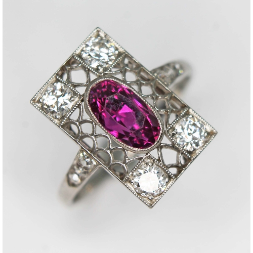 79 - An antique Art Deco period ruby and diamond cluster ring, the millegrain set oval cut purplish centr...