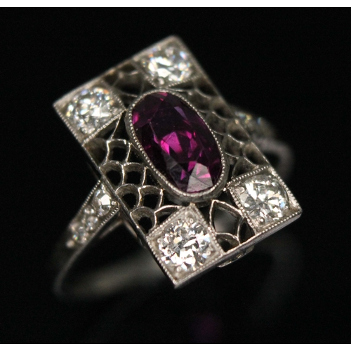 79 - An antique Art Deco period ruby and diamond cluster ring, the millegrain set oval cut purplish centr... 