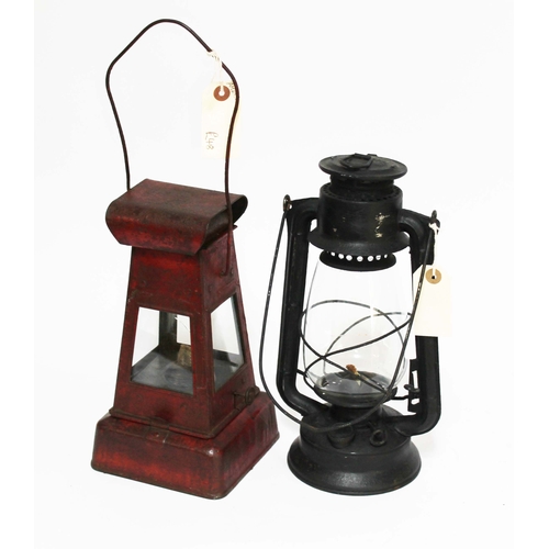 143 - A red painted metal lamp and a black storm lamp.