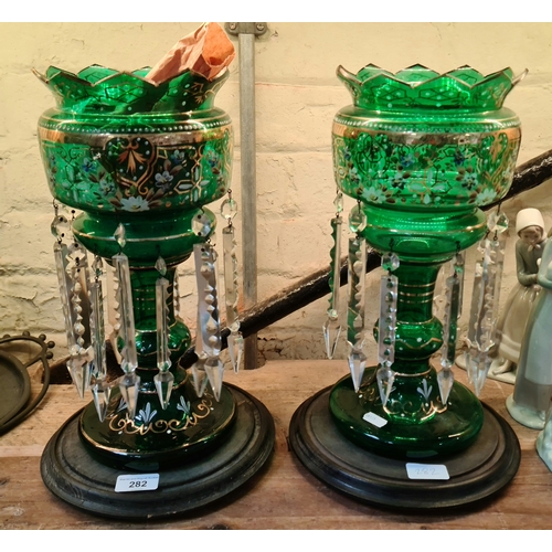 282 - A pair of Victorian green glass Mantle Vases decorated with flowers in gilt and hung with spear cut ... 