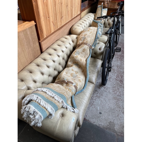 957 - A pair of cream leather chesterfield settees.