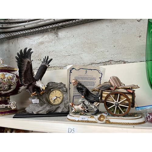 577 - A modern clock featuring and eagle, and a Capodimonte figure of the Second Hand Dealer (damaged)