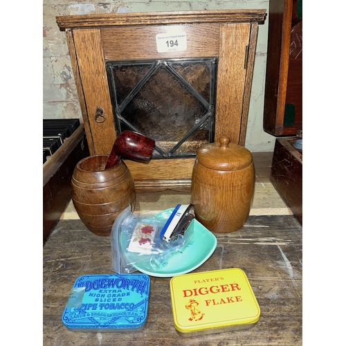 194 - An oak and leaded glass smokers cabinet together with a wooden lidded tobacco jar, wooden barrel spi... 