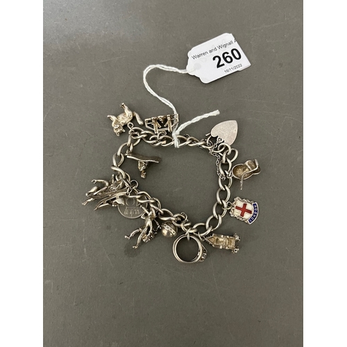 260 - A silver charm bracelet with various novelty charms to include cherub, cat, Aladdin, London Bridge, ... 