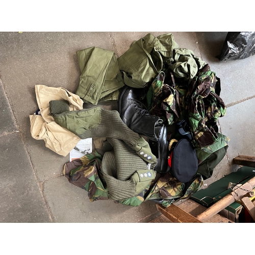 431 - A bag of military clothing including trousers, boots, peaked cap, sweater, camouflage wear, beret, s... 