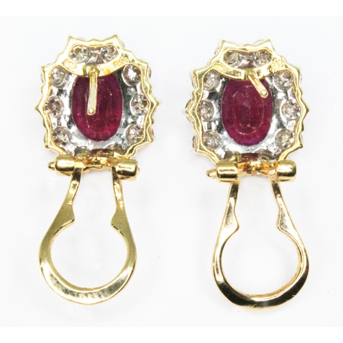 15 - A pair of diamond and flux-healed ruby earrings, the oval clusters measuring approx. 13.80mm x 12.10... 