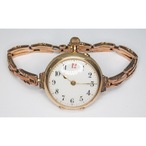 100 - A ladies enamel back wristwatch marked '14c', strap marked '9c', gross wt. 29.5g.