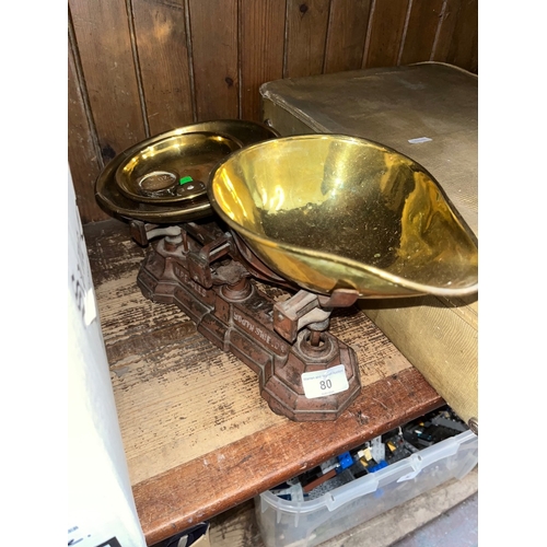 80 - A vintage cast metal set of weighing scales with brass trays and few weights.