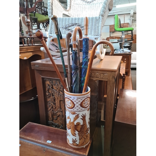 948 - A ceramic stick stand containing a number of sticks and umbrellas.