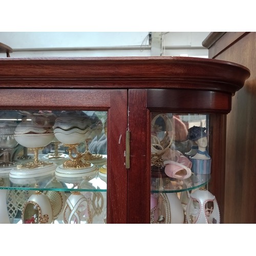 1041 - A glass display cabinet containing a number of collectable decorative eggs.