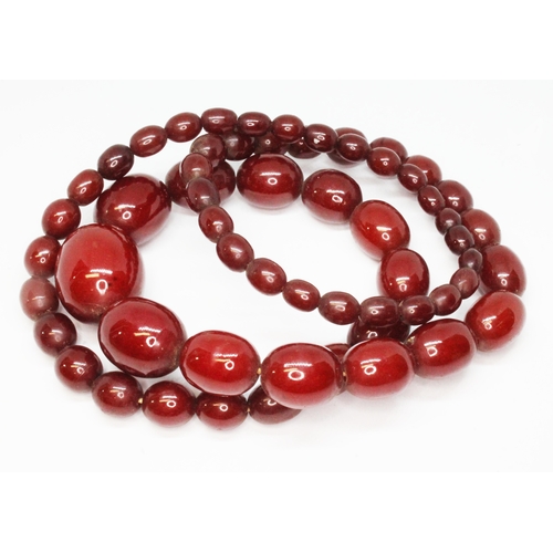 54 - A single strand of graduated marbled cherry bakelite beads, ranging in length from approx. 8mm to 28... 