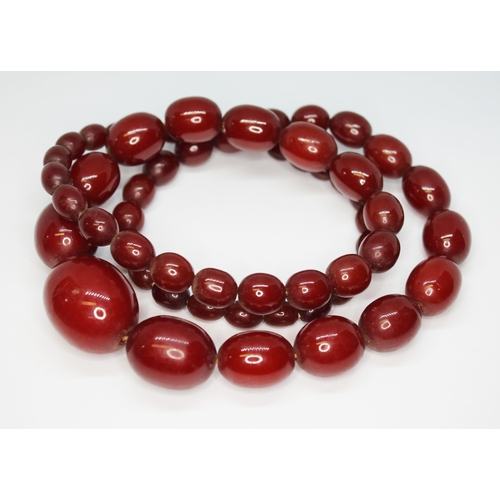 54 - A single strand of graduated marbled cherry bakelite beads, ranging in length from approx. 8mm to 28... 