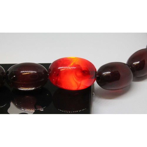 10 - A graduated marbled cherry bakelite bead necklace, the beads ranging in length from approx. 12mm to ... 