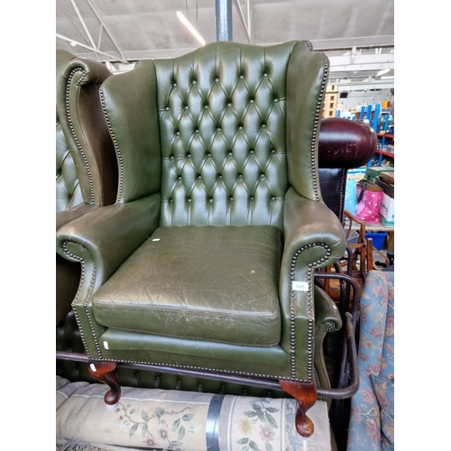 1045 - A green leather Chesterfield wingback armchair. The upholstery may not comply with the Furniture and... 