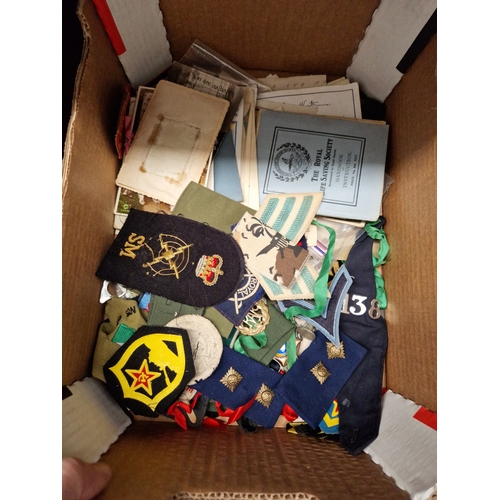 67 - A box of ephemera, postcards and assorted military badges etc.