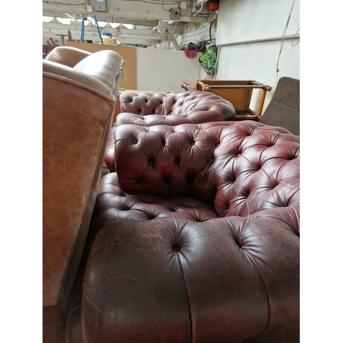 1014 - A pair of oxblood red leather Chesterfield club chairs.