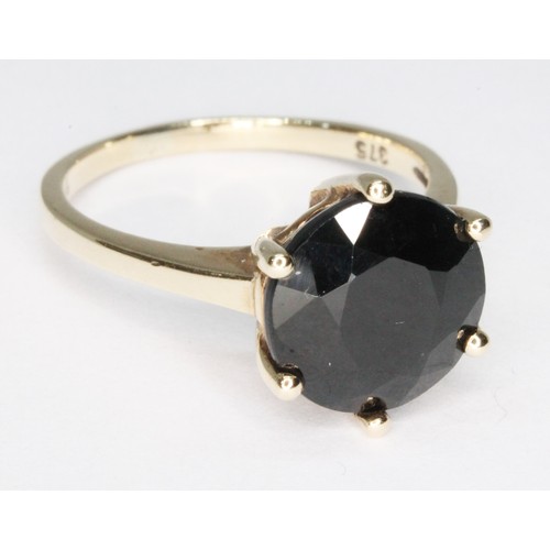 14 - A 9ct gold sapphire solitaire ring, the dark blue/black round mixed cut stone measuring approx. 10mm... 