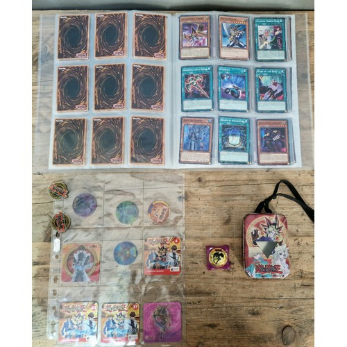 371 - Binder of Yu-Gi-Oh cards with vintage Yu-Gi-Oh pin badges, tin, tazis, etc. sold as seen no returns.