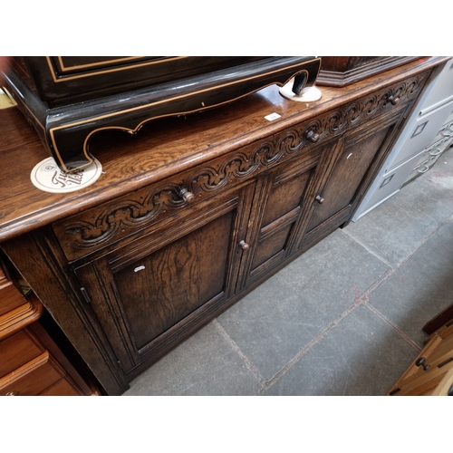 938 - A aged oak sideboard with carved detail to the drawers.