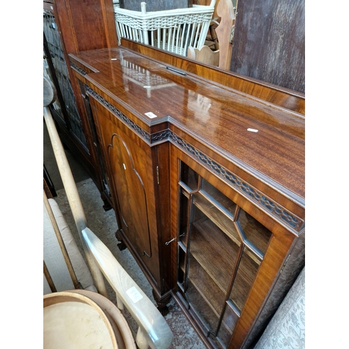 963 - A glazed mahogany breakfront cabinet standing on ball and claw feet.