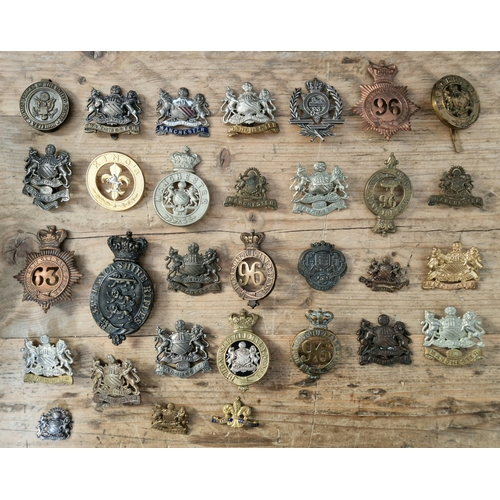 61 - A collection of military cap badges and plates to include Manchester Regiment, 33rd Lancashire Rifle... 