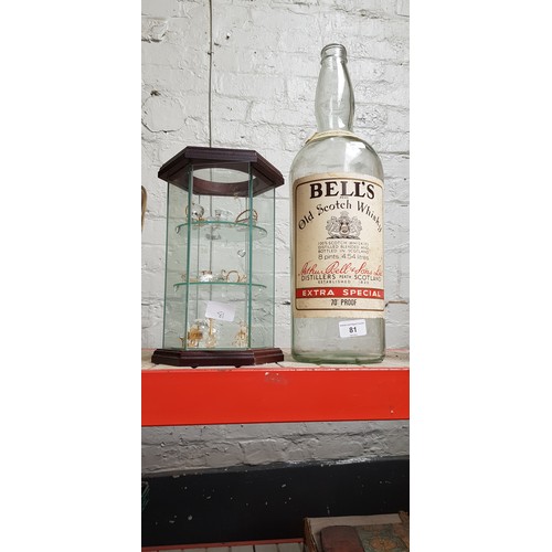 81 - A 1 gallon Bell's bottle together with a hexagonal glass display cabinet containing various Swarovsk... 