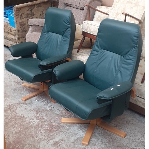 770 - A pair of green faux leather swivel chairs with stools.