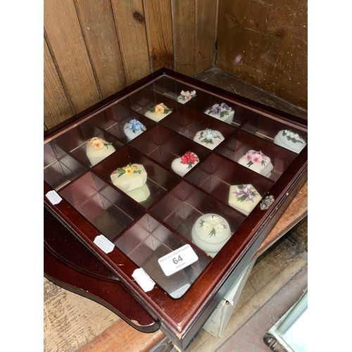 64 - A display case containing Capodimonte Flower of the month trinket boxes