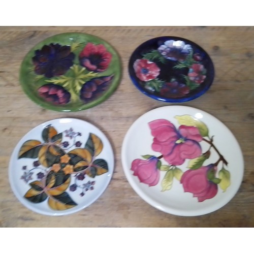 64 - Four Moorcroft pottery plates, diameter 21cm & 26cm.