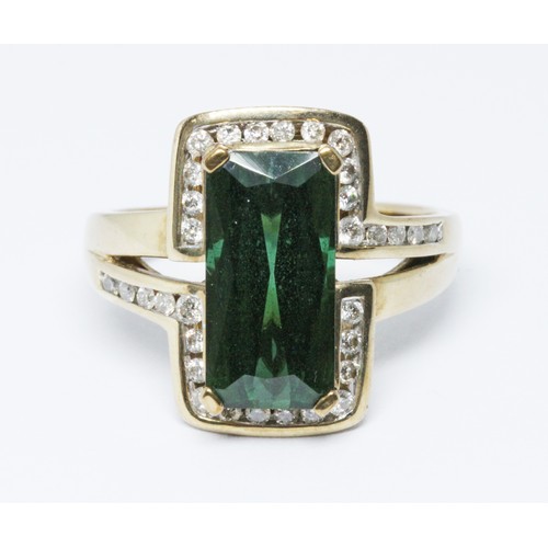 33 - A green tourmaline and diamond ring, the central rectangular cut stone weighing approx. 4.50cts, set... 